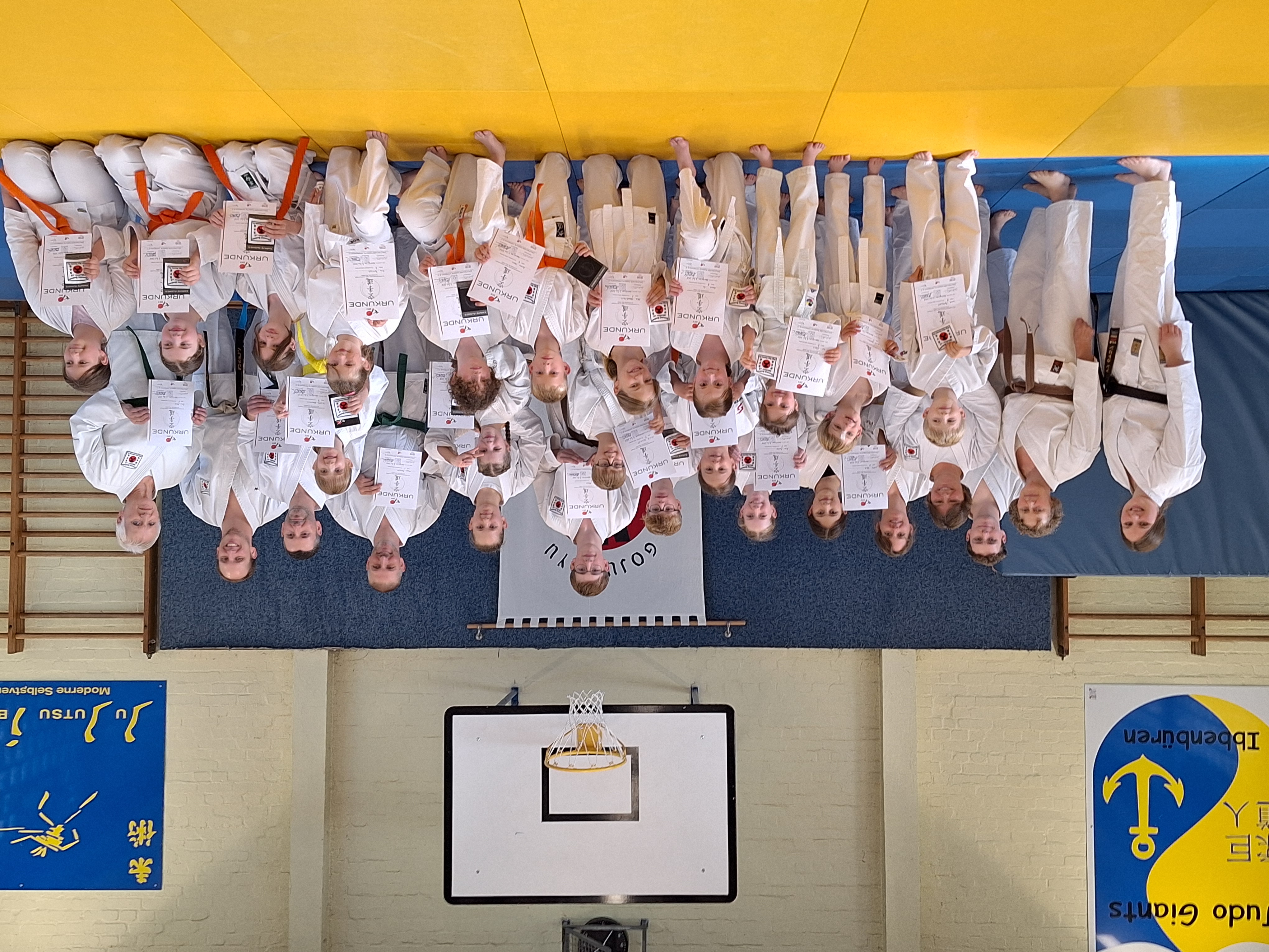 Eine Gruppe von Kindern und Erwachsenen freuen sich über eine bestandene Karate Prüfung.